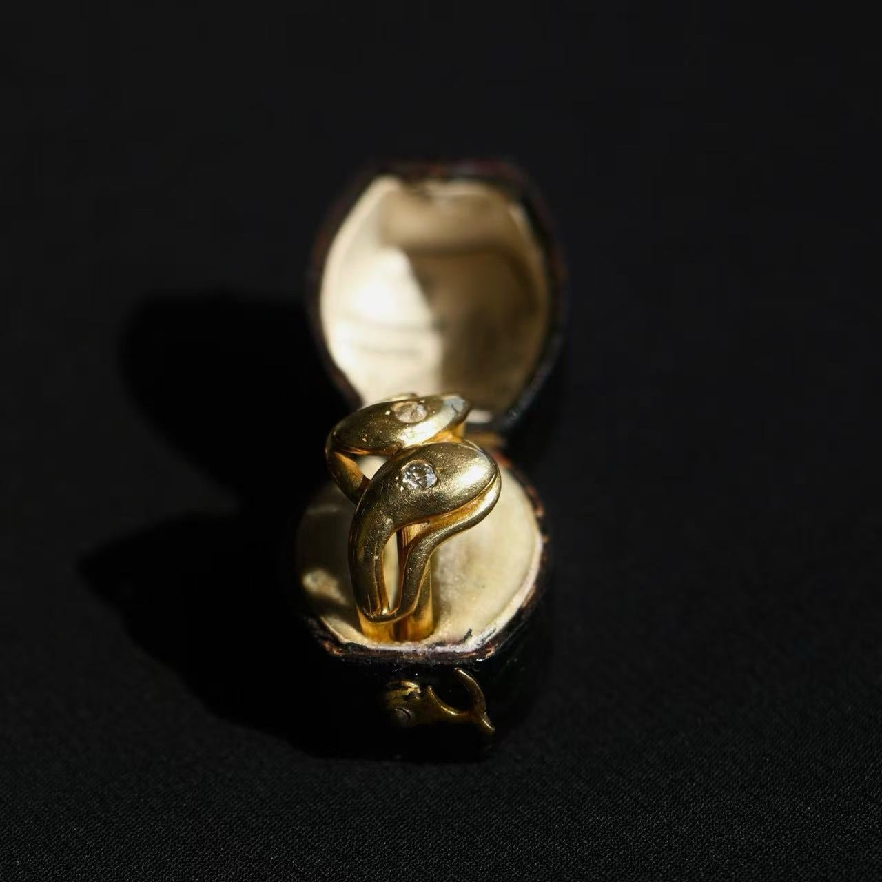 Gold ring with a diamond in an open box on a black background